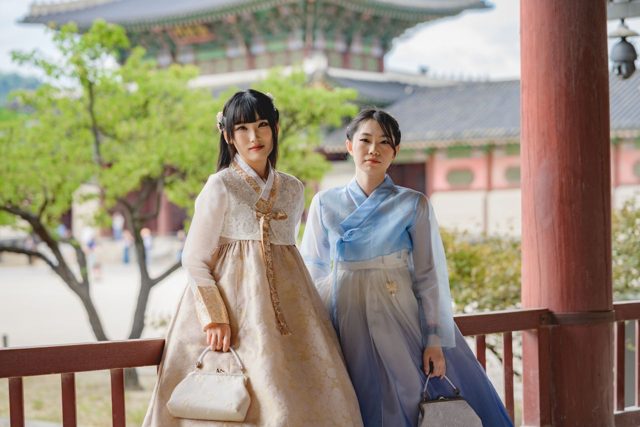 Two friends in hanbok standing by a palace railing